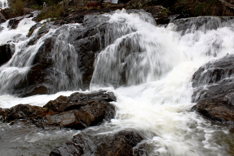 Nước chảy xuống xói vào đá tạo bọt trắng xóa...